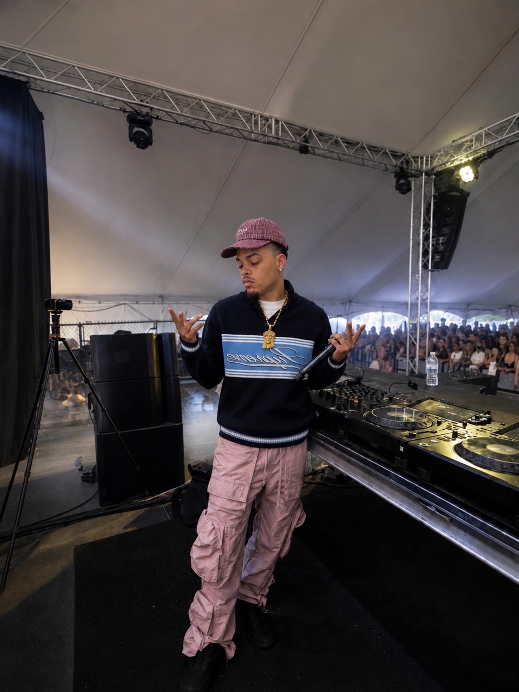 CJ WestCoast at the DJ decks on a festival stage with the crowd behind him
