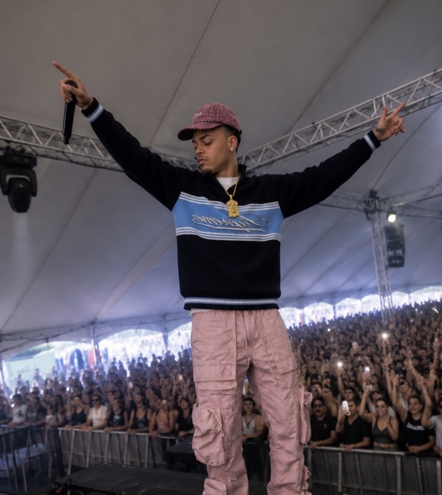 CJ WestCoast with arms outstretched and a microphone in front of a packed festival tent